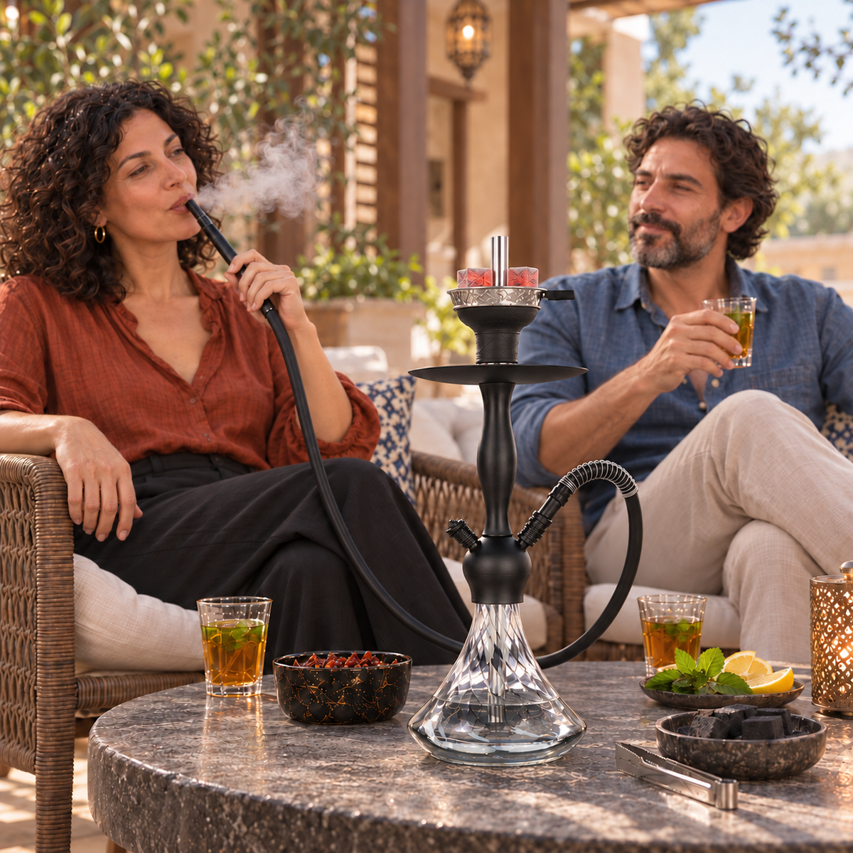 Aladin Alux Captain Black Wave shisha pipe with an adult couple, flavour and charcoal in a covered veranda setting.