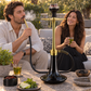 Oduman Cosmo black glass and gold shisha pipe in a garden setting with adults, flavour, charcoal and tongs.